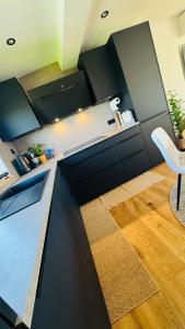 a kitchen with black cabinets and a wooden floor at Klimatisierte Komfort-Eifel-Ferienwohnung Mechernich, Obergartzem, Satzvey - nahe Krewelshof, Burg Satzvey & Phantasialand in Mechernich +27 photos