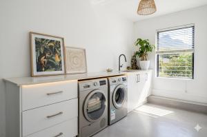 a laundry room with a washer and dryer at LA HACIENDA - MODERN, BRIGHT, STYLISH House with Private Pool in Cape Town