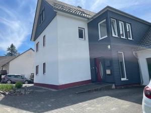 a white and black house with a car parked at Bei Kleins in Nümbrecht