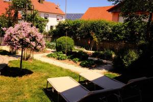 a garden with two benches and a tree with pink flowers at Ferienwohnung zum Utzen in Berching