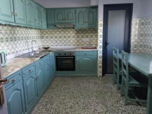 a kitchen with green cabinets and a sink and a table at Meda`s House in Meda