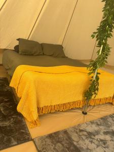a bed in a tent with a yellow blanket at Cornwalls Glamping Tent in Delabole