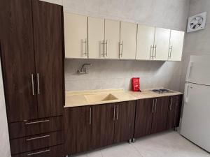 a kitchen with wooden cabinets and a sink and a refrigerator at أجنحة السمو in Hail