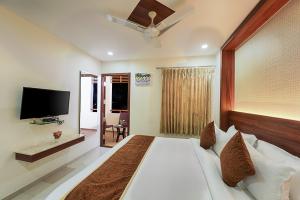 a bedroom with a large white bed and a flat screen tv at Holiday Residency Coimbatore in Coimbatore