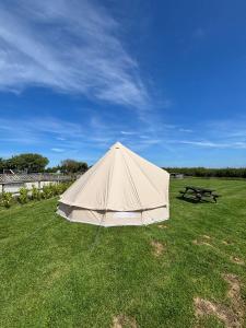 a large tent in a field with a picnic table at Cornwalls Glamping Tent in Delabole