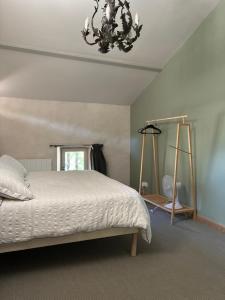 a bedroom with a white bed and a chandelier at La croix des granges - le gîte in Chapdeuil +47 photos
