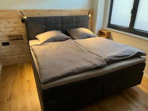 a bed in a bedroom with a gray headboard at Ferienwohnung Heiterwang in Heiterwang