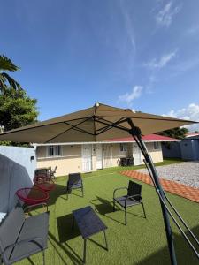 a patio with chairs and an umbrella on the grass at Casa Nalya in Kourou