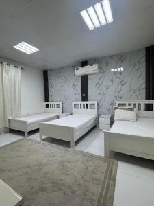 a room with three beds and a wall with marble at استراحة الصقر in Khor Fakkan