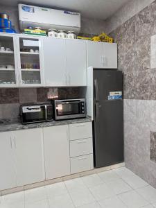a kitchen with white cabinets and a black refrigerator at استراحة الصقر in Khor Fakkan