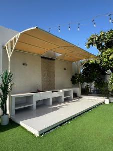 a pavilion with white benches in a garden at استراحة الصقر in Khor Fakkan