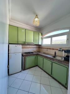 a kitchen with green cabinets and a white refrigerator at Cozy Flat With Pool Near The Beach TAMRAGHT -APP13 in Tamraght Ouzdar +18 photos