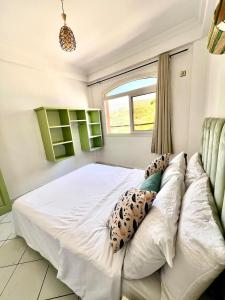 a bedroom with a white bed and a window at Cozy Flat With Pool Near The Beach TAMRAGHT -APP13 in Tamraght Ouzdar