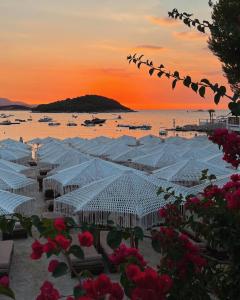 a group of white umbrellas on the beach at sunset at Dimora Seaside Apartments in Ksamil
