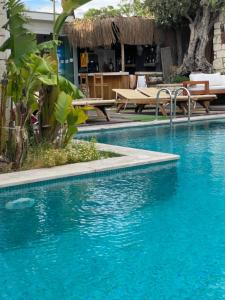 a swimming pool with blue water and tables and benches at Chloe hotel Alaçatı in Alaçatı