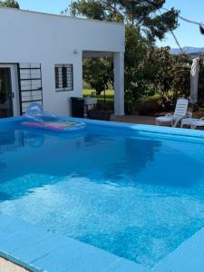 a large blue swimming pool with a house in the background at Tossal del Pla in Estivella +7 photos