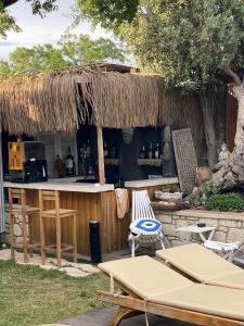 an outdoor bar with a straw roof and two chairs at Chloe hotel Alaçatı in Alaçatı