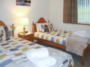 a bedroom with two beds and a table with a lamp at The Old Store in Onich +1 photo