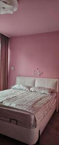 a bedroom with a bed with a pink wall at ОмниЯ Терас in Chernomorets