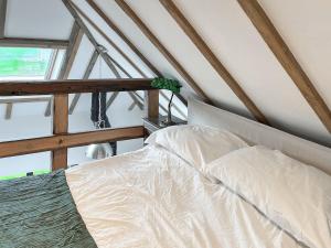 a bed with white sheets in a attic at Landberrick Farm Bothy 2 in Newton Stewart