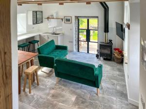 a kitchen and living room with green chairs and a table at Landberrick Farm Bothy 2 in Newton Stewart