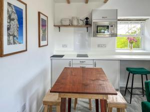 a kitchen with a wooden table in front of a counter at Landberrick Farm Bothy 2 in Newton Stewart +6 photos