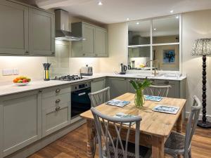 a kitchen with green cabinets and a wooden table at Grange Cottage in Langham