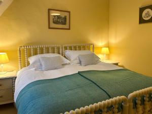 a bedroom with a large bed with two lamps at Grange Cottage in Langham +4 photos