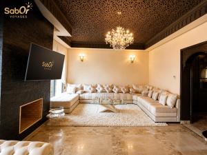 a living room with a couch and a chandelier at Villa Yacout Marrakech -Private Pool in Sraghna