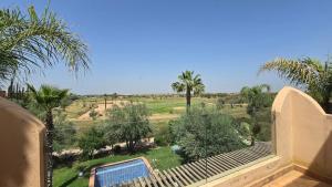 a balcony with a view of a field and palm trees at Villa Yacout Marrakech -Private Pool in Sraghna