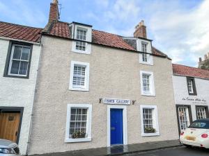 a house with a blue door on a street at Fisher Gallery in Pittenweem