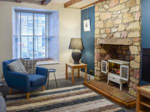 a living room with a blue chair and a stone fireplace at Fisher Gallery in Pittenweem +14 photos