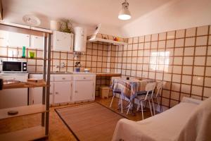 uma cozinha com mesa e cadeiras num quarto em Hostel Seixe em Odeceixe