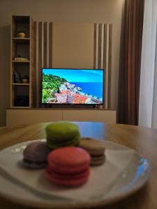 four cookies on a plate on a table with a television at A&B Seaside Residence in Golem +14 photos