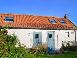a white house with an orange roof and blue doors at Haven Cottage - E4342 in Holy Island