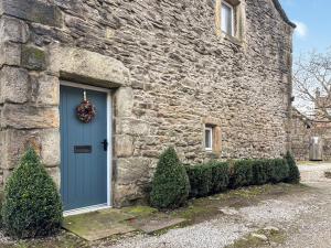a blue door on the side of a stone building at Pletts Barn in Grassington
