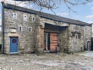an old stone building with a blue door at Pletts Barn in Grassington