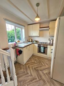 a kitchen with white cabinets and wooden floors at Holly Cottage in Edwinstowe