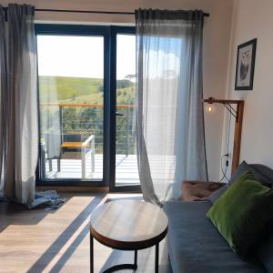 ein Wohnzimmer mit Sofa, Tisch und Balkon in der Unterkunft HUUT in Zlatibor