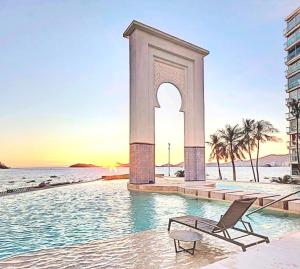 a chair in the water in front of a monument at Playa Acapulco Espectacular Apartment in Acapulco