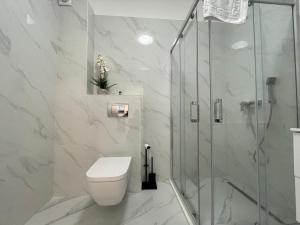 a bathroom with a toilet and a glass shower at Apartament Madagascar Hotel BS by Ella Mamaia Nord in Mamaia Sat/Năvodari