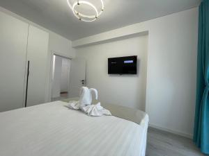 a bedroom with a bed with white sheets and a tv at Apartament Madagascar Hotel BS by Ella Mamaia Nord in Mamaia Sat/Năvodari +28 photos
