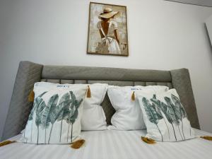 a bed with white pillows and a painting on the wall at Apartament Madagascar Hotel BS by Ella Mamaia Nord in Mamaia Sat/Năvodari
