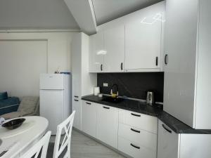 a kitchen with white cabinets and a white refrigerator at Apartament Madagascar Hotel BS by Ella Mamaia Nord in Mamaia Sat/Năvodari