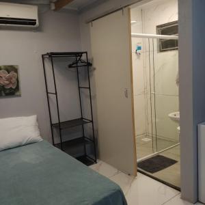 a bedroom with a bed and a glass shower at Small and cozy in Ijuí