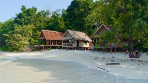 a couple of houses on a beach next to the water at Batanta Panorama Homestay in Dayang