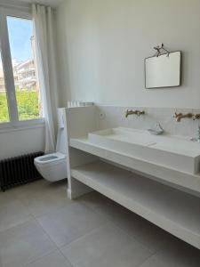 a white bathroom with a sink and a toilet at Grande maison familiale rénovée en 2025 in Versailles +6 photos