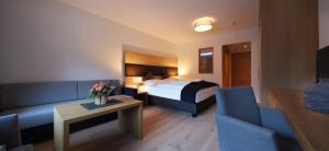 エールヴァルトにあるAppartementhaus Sonnenhangのベッド、ソファ、テーブルが備わるホテルルームです。
