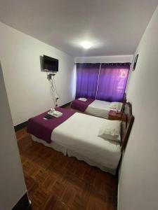a bedroom with two beds and a window with purple curtains at Zigal hotel in Antofagasta