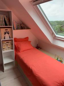 a bedroom with a red bed and a window at Gite Gavotte in Concarneau